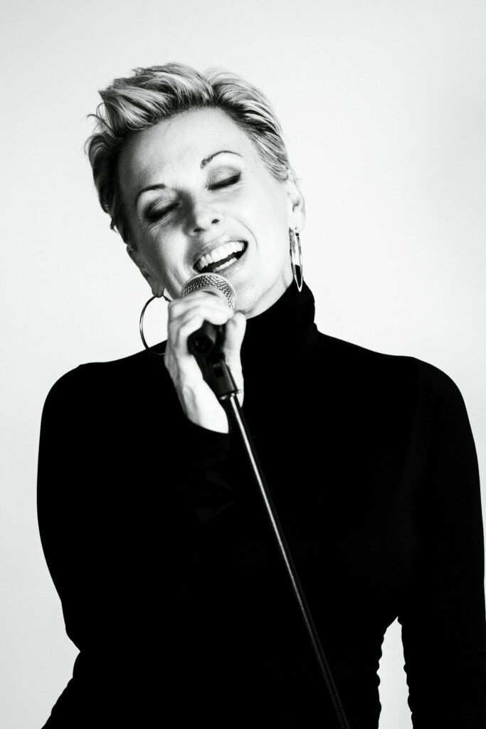 Angela Kelman singing into a Microphone Black & White